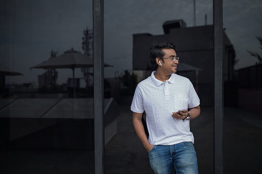 Man with wireless earbuds standing by glass window