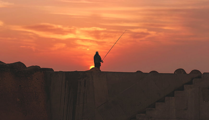Silhouette of Man Fishing on Pier at Sunset