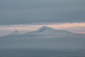 Snowy Volcanoes Rising Above Sea of Fog at Dawn