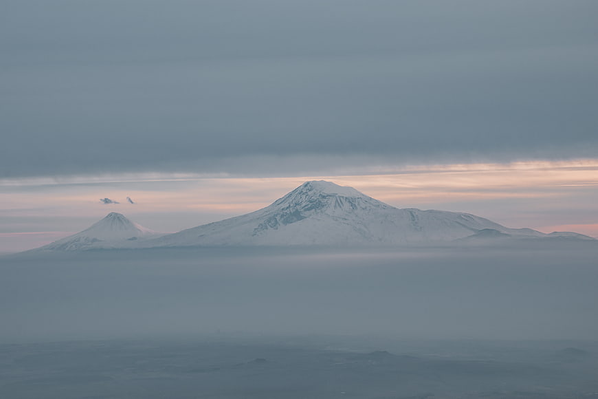 Snowy Volcanoes Rising Above Sea of Fog at Dawn