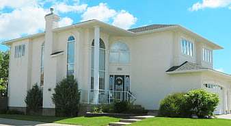 White Suburban House Exterior With Landscaped Lawn And Blue Sky