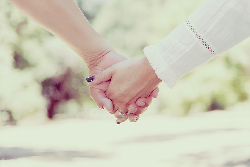 Couple Holding Hands Outdoors with Engagement Ring