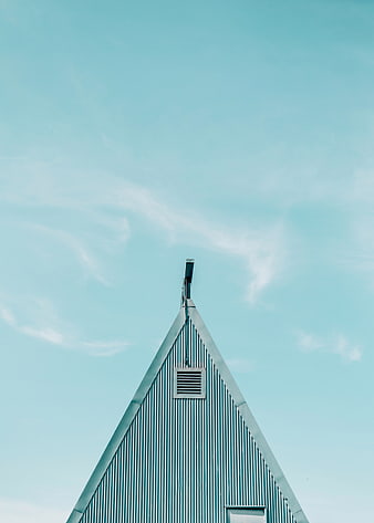 Teal corrugated metal roof peak against blue sky