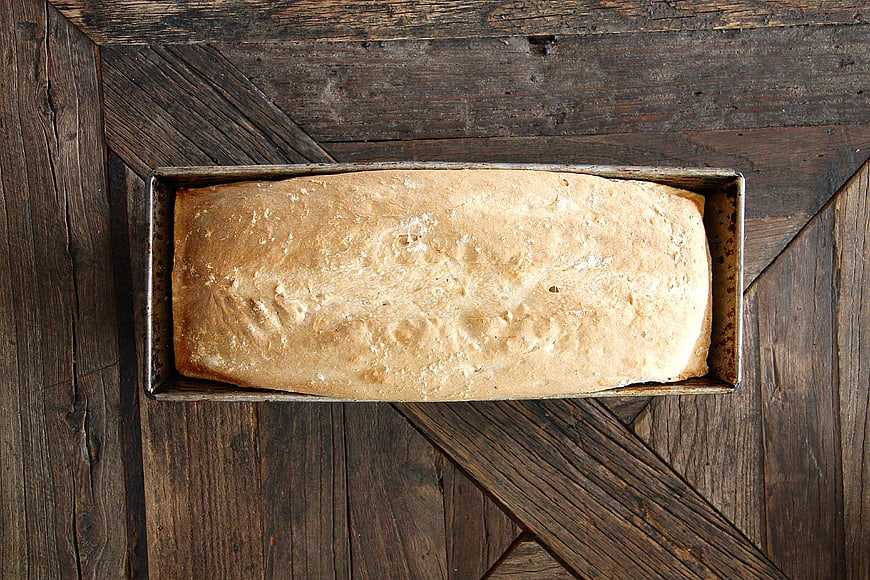 Freshly Baked Loaf of Bread in Pan on Rustic Wood