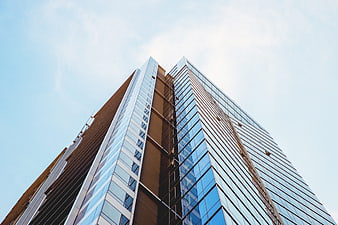 Low angle view of modern glass skyscraper against blue sky