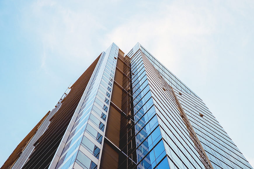 Low angle view of modern glass skyscraper against blue sky