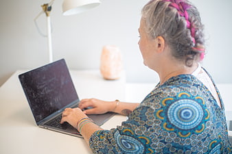 Senior Woman Typing on Laptop at White Desk