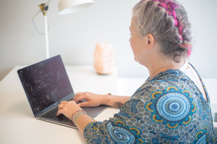 Senior Woman Typing on Laptop at White Desk