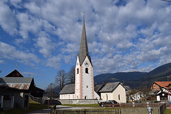 White church with tall spire in alpine village