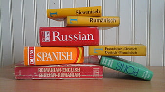 Stack of vintage language dictionaries on wooden table