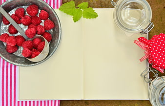 Fresh raspberries and recipe book with mason jars for jam making