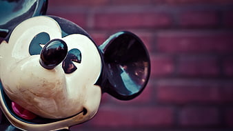 Close-up of vintage Mickey Mouse figure against brick wall