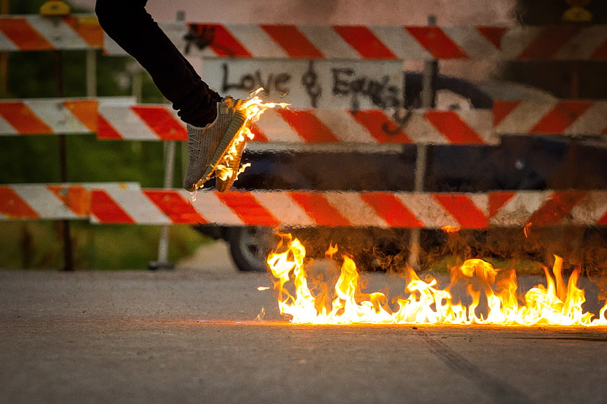 Sneaker Jumping Over Fire on Asphalt Street