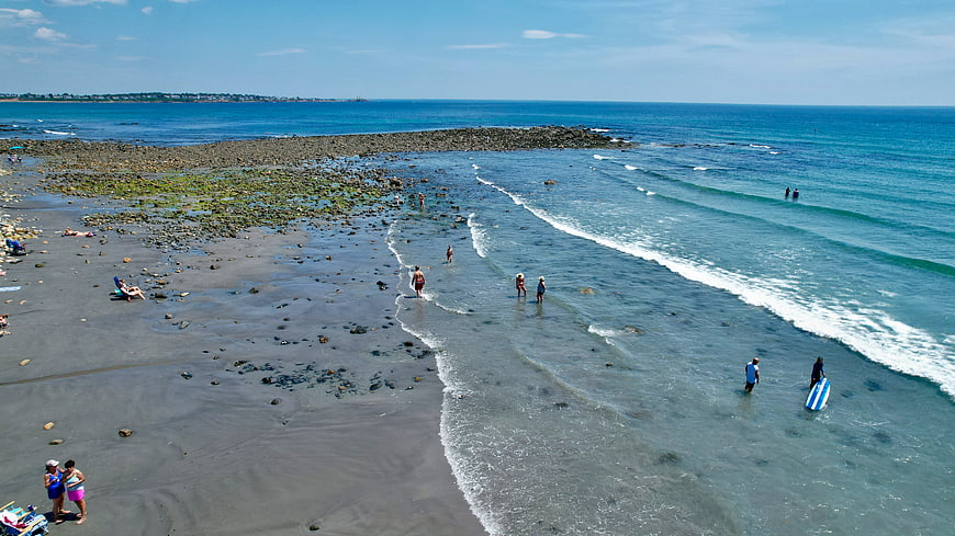 Aerial View of Rocky Beach with People Swimming and Relaxing
