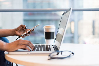 Woman working on laptop and smartphone with coffee