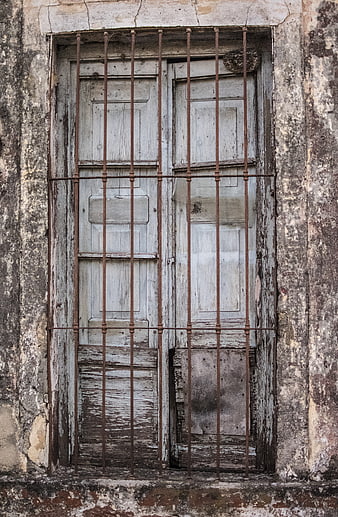 Weathered wooden window with rusty iron bars on old wall