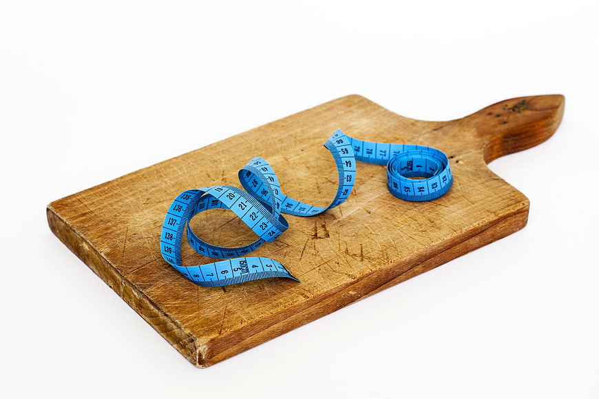 Blue measuring tape on wooden cutting board for diet concept