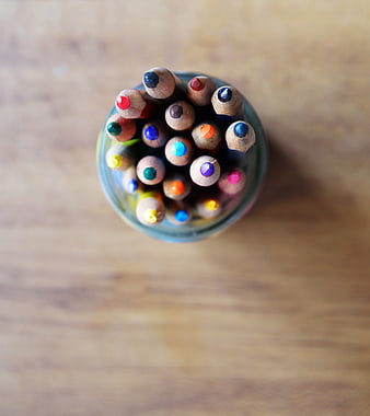 Top View of Colored Pencils in Glass Jar on Wood