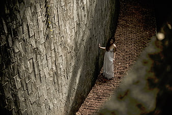 Woman in White Dress Standing in Narrow Stone Alley
