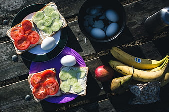 Healthy camping breakfast with sandwiches, eggs, and fruit on wooden table