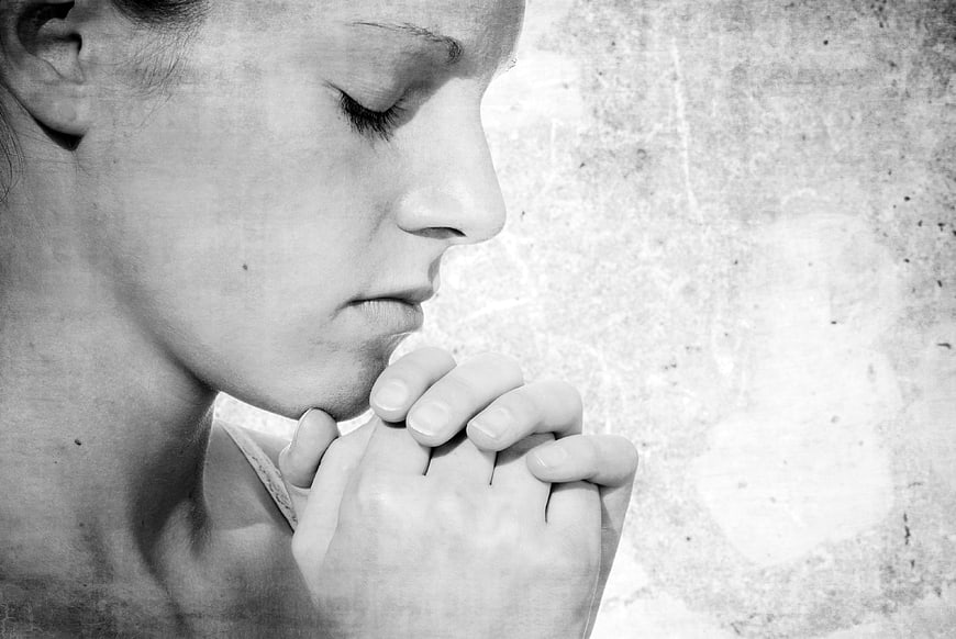 Black and white portrait of woman praying with closed eyes