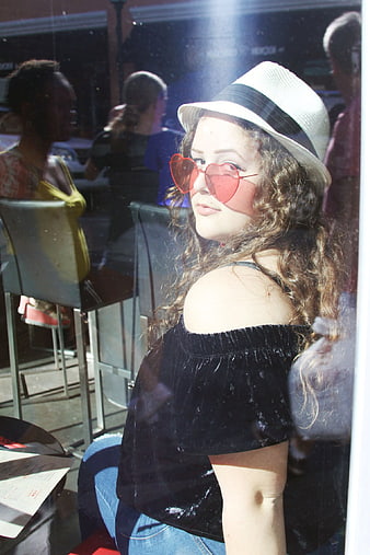 Woman with Heart Sunglasses and Fedora in Cafe