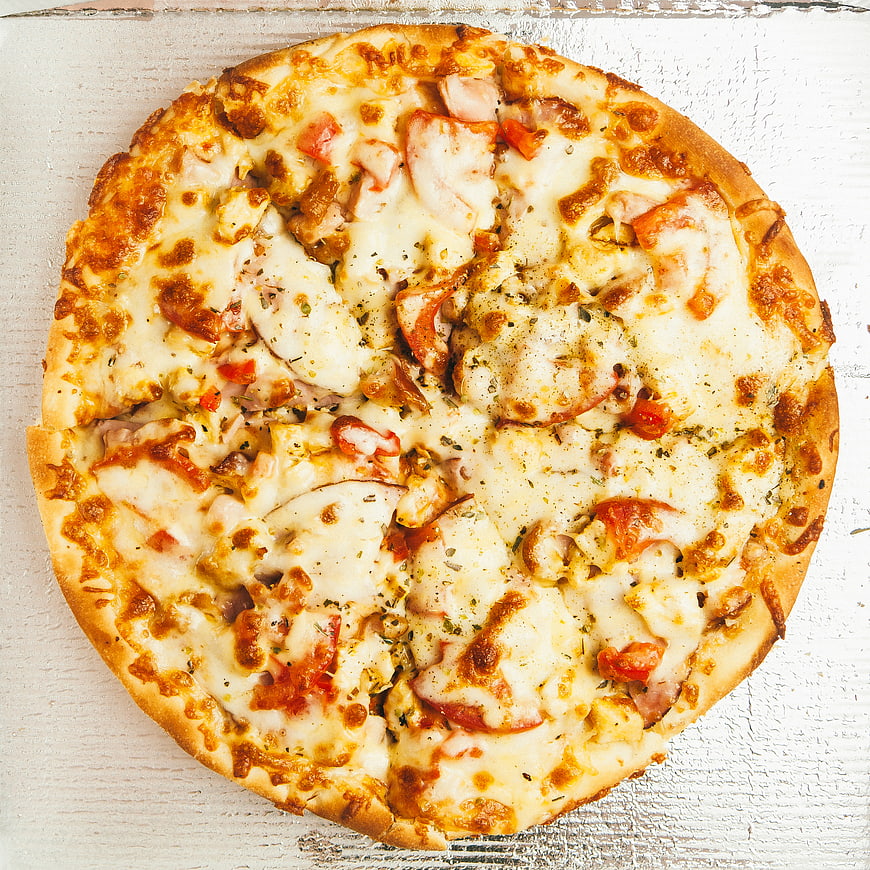 Top View of Homemade Chicken and Tomato Pizza on White Wood