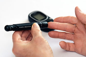 Senior hands using a blood glucose meter and lancet device