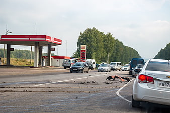 Traffic accident scene with debris on highway near gas station