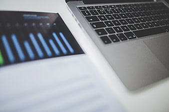 Laptop Keyboard and Blurred Business Chart on Desk