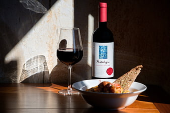 Red wine bottle and glass with rustic lunch bowl