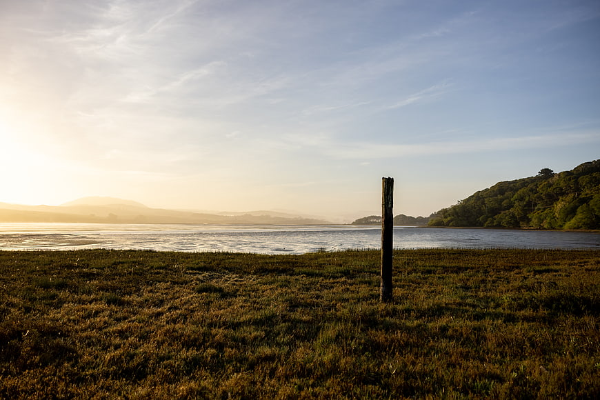 Serene coastal landscape with wooden post at sunrise