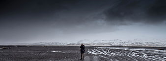 Lone Photographer on Black Sand Beach with Snowy Mountains