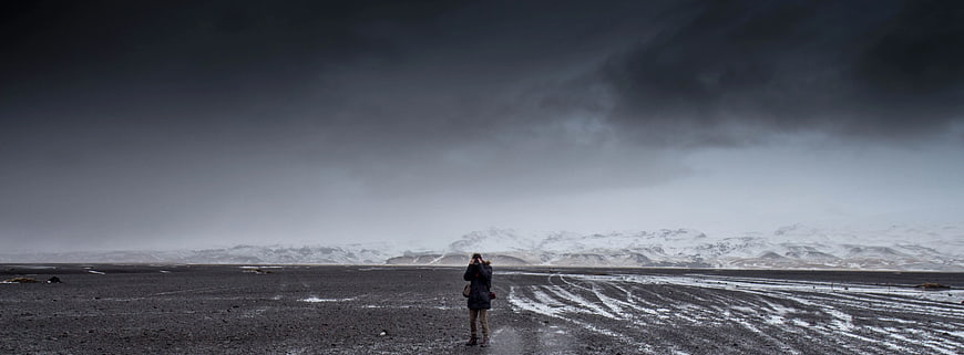 Lone Photographer on Black Sand Beach with Snowy Mountains