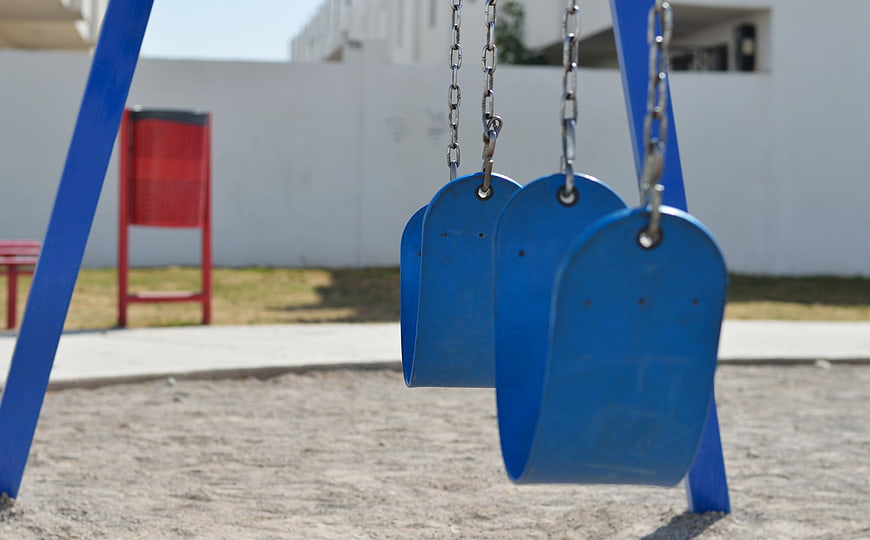 Empty blue bucket swings hanging in a sunny playground