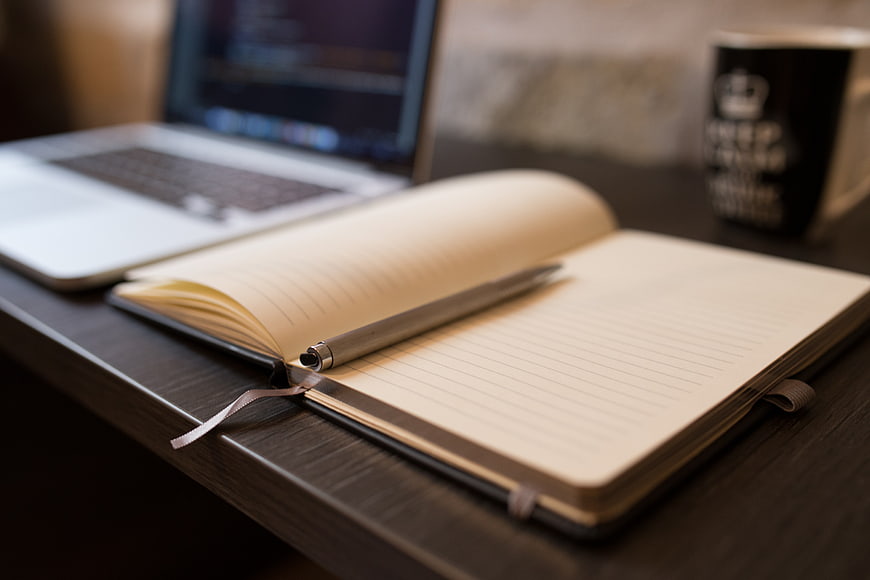 Open Notebook and Pen on Desk with Laptop
