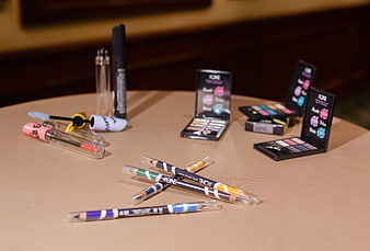 Assorted makeup products and cosmetics on beige table