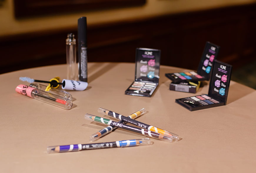 Assorted makeup products and cosmetics on beige table