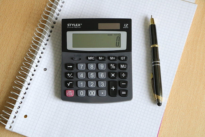 Black calculator and pen on grid notebook