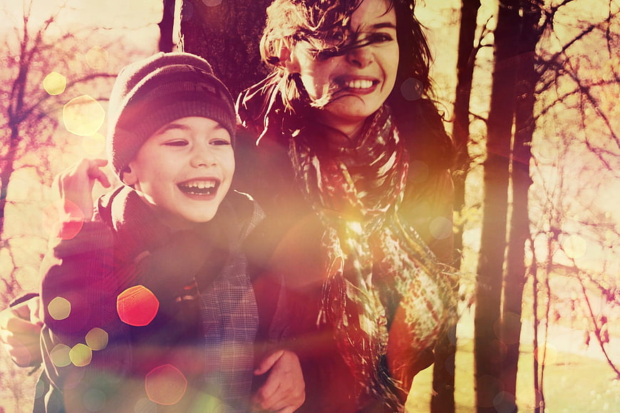 Happy Mother and Son Laughing in Autumn Forest