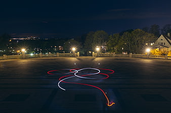 Red and white light painting trails on a stone terrace at night