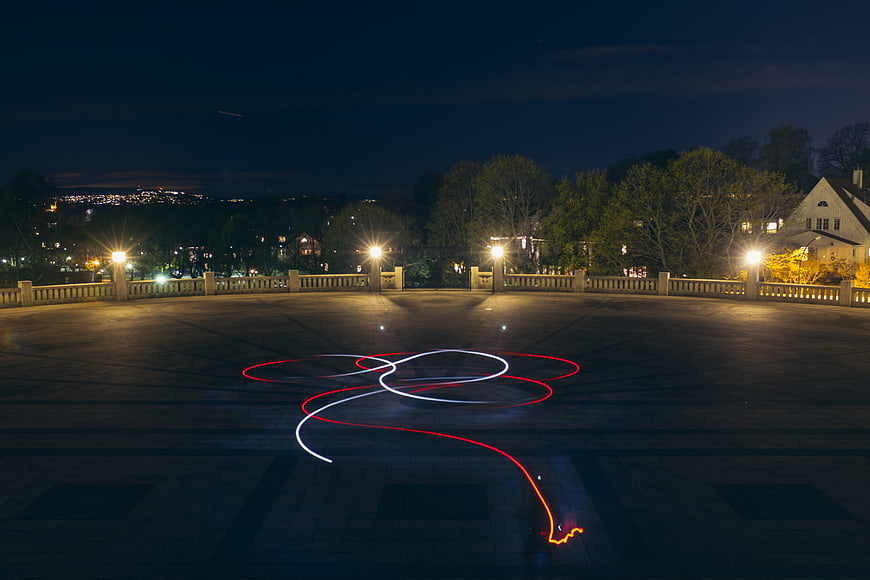Red and white light painting trails on a stone terrace at night