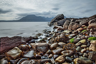 Long Exposure Rocky Shoreline with Misty Mountains