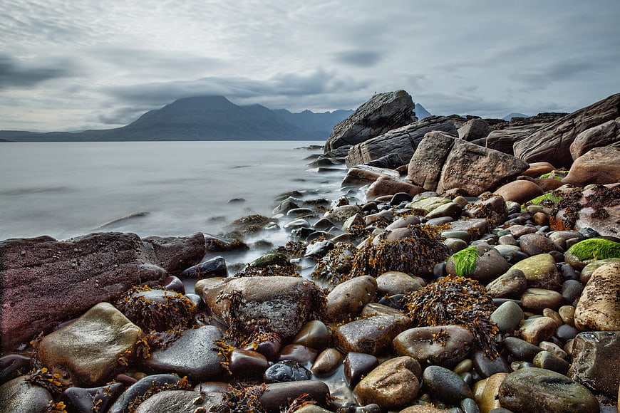 Long Exposure Rocky Shoreline with Misty Mountains