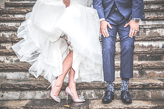 Wedding couple sitting on stone steps with pink heels and patterned socks