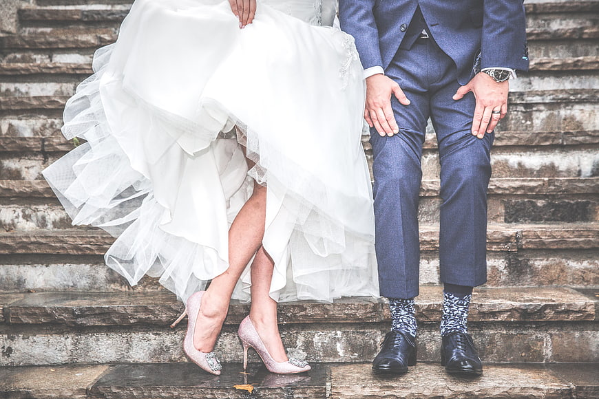 Wedding couple sitting on stone steps with pink heels and patterned socks