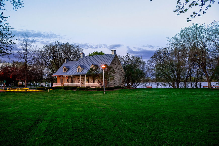 Stone house with metal roof near lake at dusk