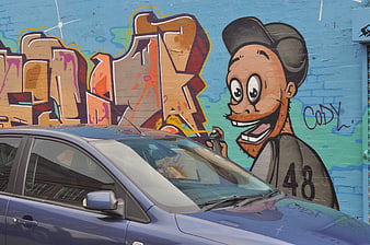 Blue car parked in front of colorful graffiti mural