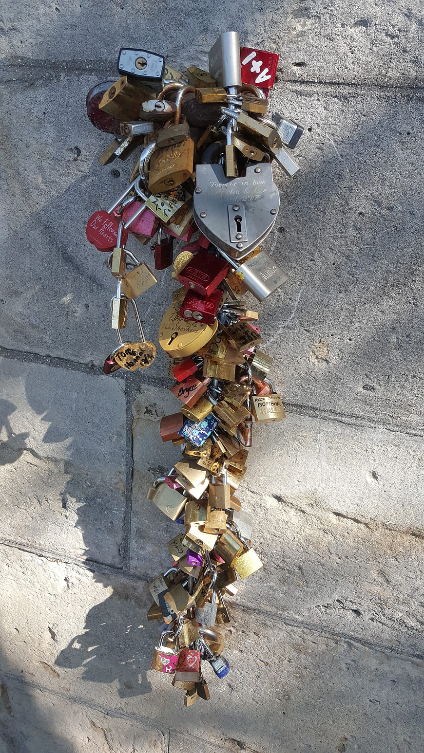 Cluster of colorful love padlocks on concrete wall