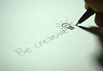 Hand writing be creative with lightbulb icon on paper